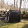 En Biokub 420 liter vid en stenmur i en solig trädgård